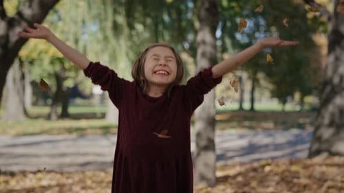 Portrait of smiling little girl which throwing up autumn leaves. Shot with RED helium camera in 8K.