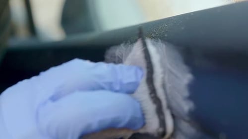 Nettoyage de l'intérieur de la voiture, des portes en cuir, avec un tampon à récurer en microfibre et porter des gants en nitrile bleus