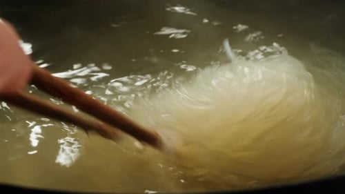 Noodles Boiling in Water Stirred With Chopsticks
