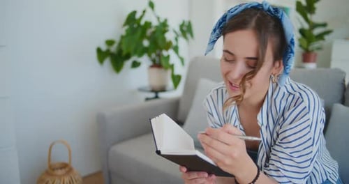 Woman Writing in a Notebook on the Couch