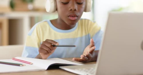 Counting fingertips, African American boy writing homework in notebook with laptop at desk