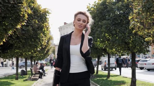 Stylish Fashion Beautiful Woman Talking on Smartphone While Walking the Street