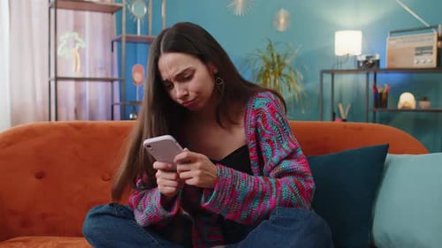 Frustrated Woman Using Smartphone on Couch Indoors