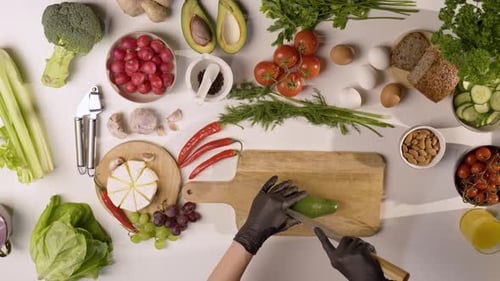 Slicing a Fresh Avocado Surrounded by Vibrant Vegetables, Fruits, and Healthy Ingredients in 4K
