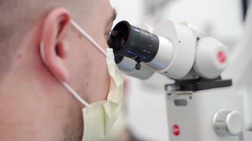 Masked Scientist Using Microscope in Laboratory Setting