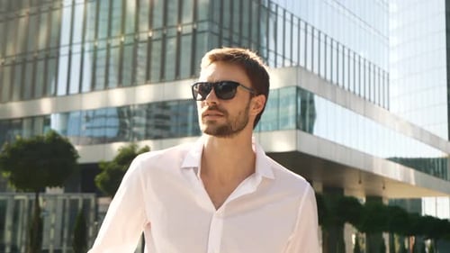 Man Smiling, Walking Past Office Building on Sunny Day