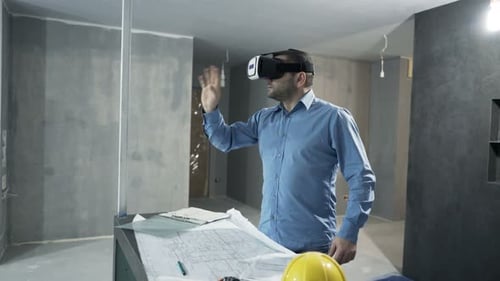 Un jeune homme explore le design d'intérieur d'une nouvelle maison avec un casque de réalité virtuelle