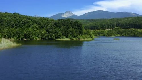 Aerial view of blue lake surrounded by forest. mountains in the background. 4K. lake in the forest.