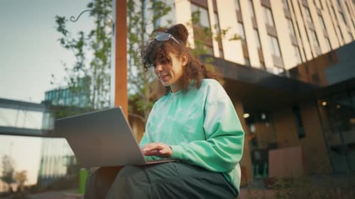 Joven programadora caucásica que trabaja fuera del patio trasero de una startup tecnológica usando una computadora portátil
