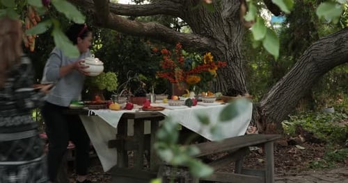 Women Bring Homemade Dishes to Set Table for Thanksgiving Dinner Garden Party