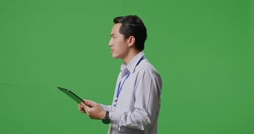 Side View Of Asian Business Man Using Tablet An Looking Around On Green Screen Background
