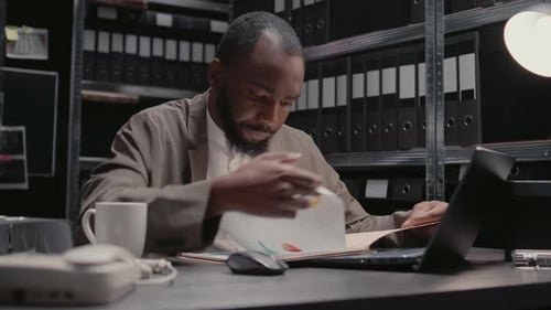 Man Analyzing Documents in an Office at Night