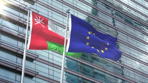 Oman and European Union Flags Waving Against Modern Building