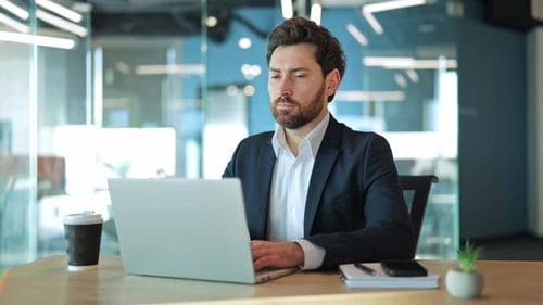 Focused Professional Working and Smiling at Office Desk