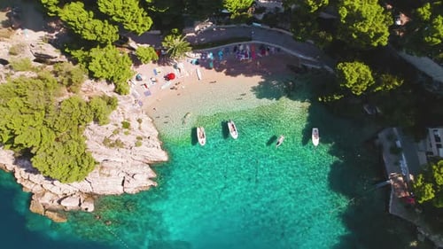 Breathtaking aerial view of pebble beach with turquoise waters and sunbathers in Brela, Croatia. Pop
