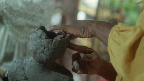 Hands Shaping Clay Sculpture in Workshop