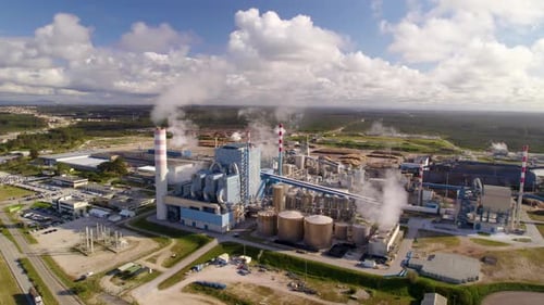 Aerial wide orbit shot of a big industrial plant on a sunny day - bird's eye view of a modern cellul