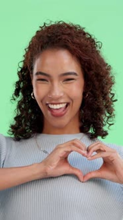 Smile, heart hand and face of woman on green screen with positivity, comfort or gratitude