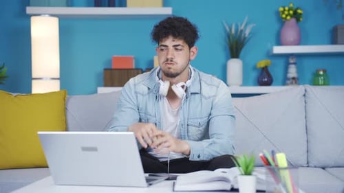 Man Putting on Headphones While Using Laptop at Home