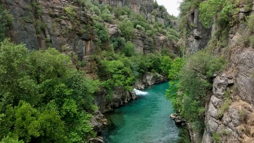 Rivière turquoise traversant un canyon verdoyant avec des falaises rocheuses abruptes