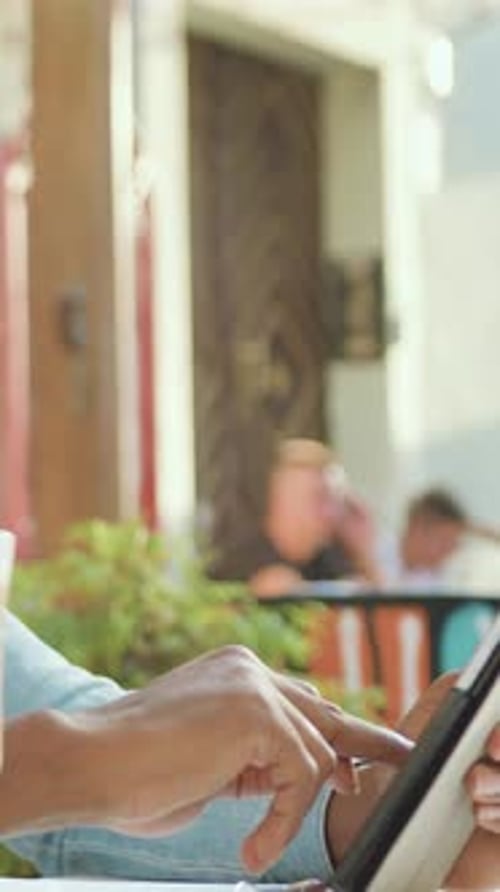 Vista aproximada de um homem bonito que está sentado em um aconchegante café ao ar livre e revisando os programas necessários em