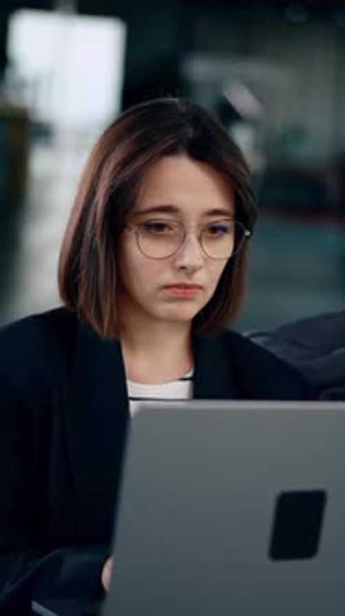 Brunette lady wearing glasses looks at laptop. Portrait of a confident businesswoman working.