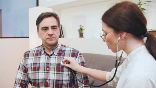 Home Doctor Examines Patient in Cozy Office Using Stethoscope During Health Checkup in a Relaxed