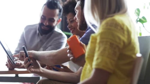 Smiling Group Looking at Mobile Devices at Work