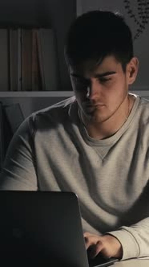 Young Man Uses Laptop in Dark Room