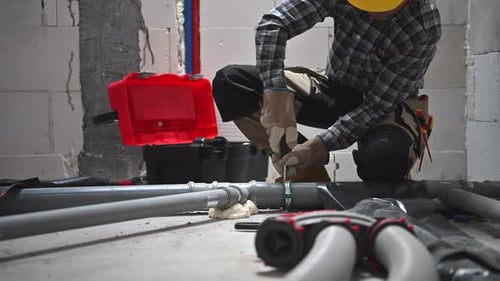 Construction Worker Tightening Pipe with Clamp