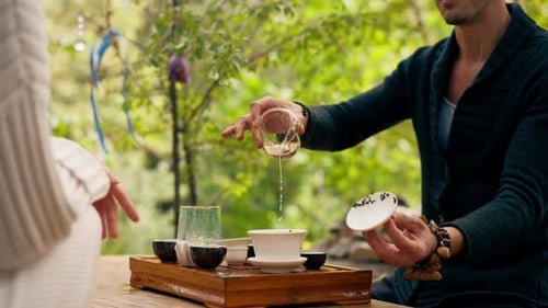 close-up The hands of a professional tea master who pours fresh natural green tea from a glass