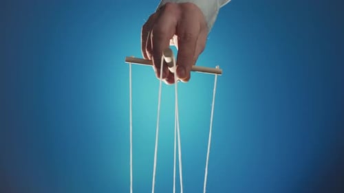 La mano del titiritero controla la marioneta con un manipulador de madera y cuerdas