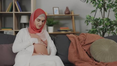 Pregnant Woman Gently Touching Stomach at Home
