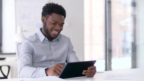 Smiling Man Working with Tablet Device in Office