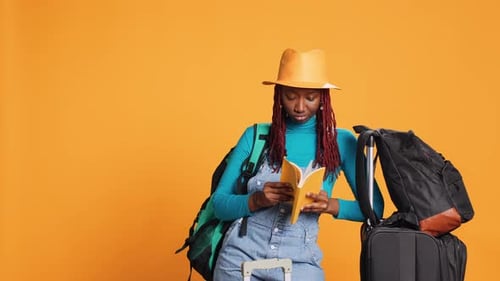 Woman Reads a Book near Suitcase