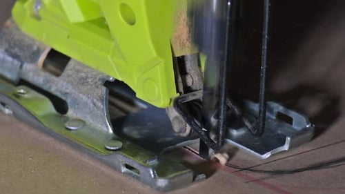 Close-up of electric jigsaw in action, men's hand cutting up wood board with a jigsaw in slow motion