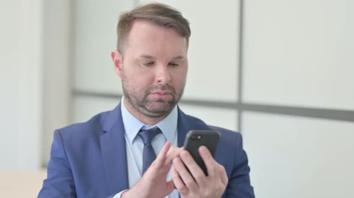 Man in Suit Using Smartphone in Office