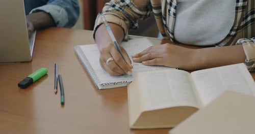 Student Taking Notes at a Desk with Books