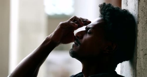 Pensive Man Leaning Against Wall in Deep Thought