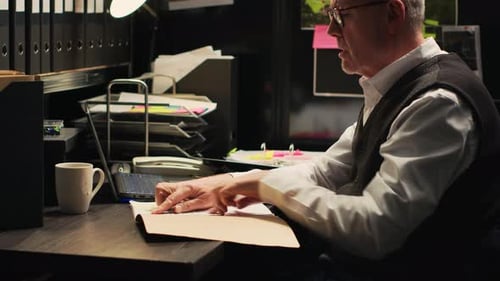 Man Reviews Paperwork at Overcrowded Office Desk