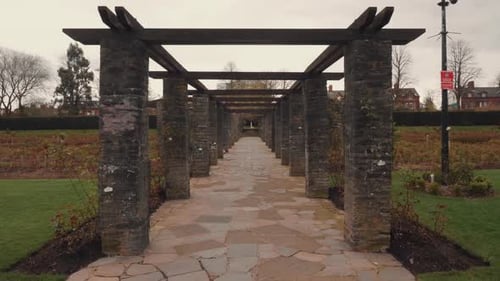 Eine symmetrische Spuraufnahme, die sich auf einen Steintunnel in einem Stadtgartenpark zubewegt