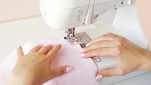 Hands Sewing Pink Fabric with a Sewing Machine