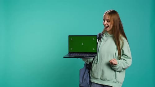 Smiling Woman Presenting Laptop with Green Screen Display