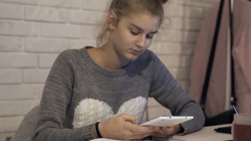 Teen Studying Using Tablet at Table Indoors