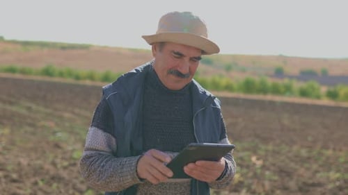 Man Uses Tablet in a Rural Field
