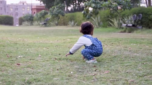 cute toddler trying to stand at park green grass from different angle