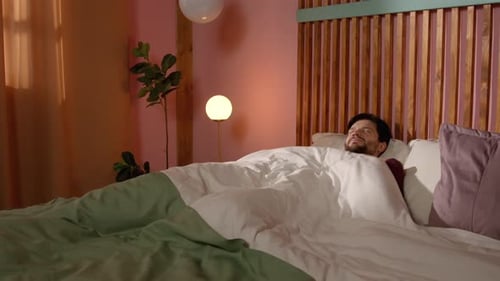 Man Wakes Up and Stretches in Bed