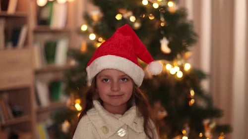 Child Smiling with Santa Hat by Christmas Tree