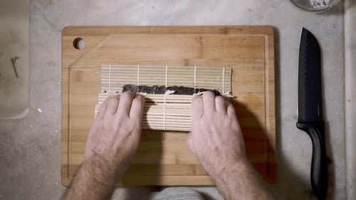 Time lapse of top down view on two hands on wooden cutting tablet on kitchen counter rolling ingredi