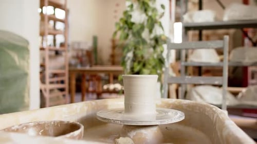 Potter's wheel with clay vase in pottery studio